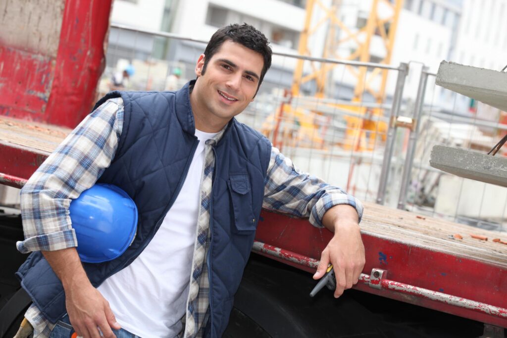 a man standing next to a truck holding a blue hard hat"